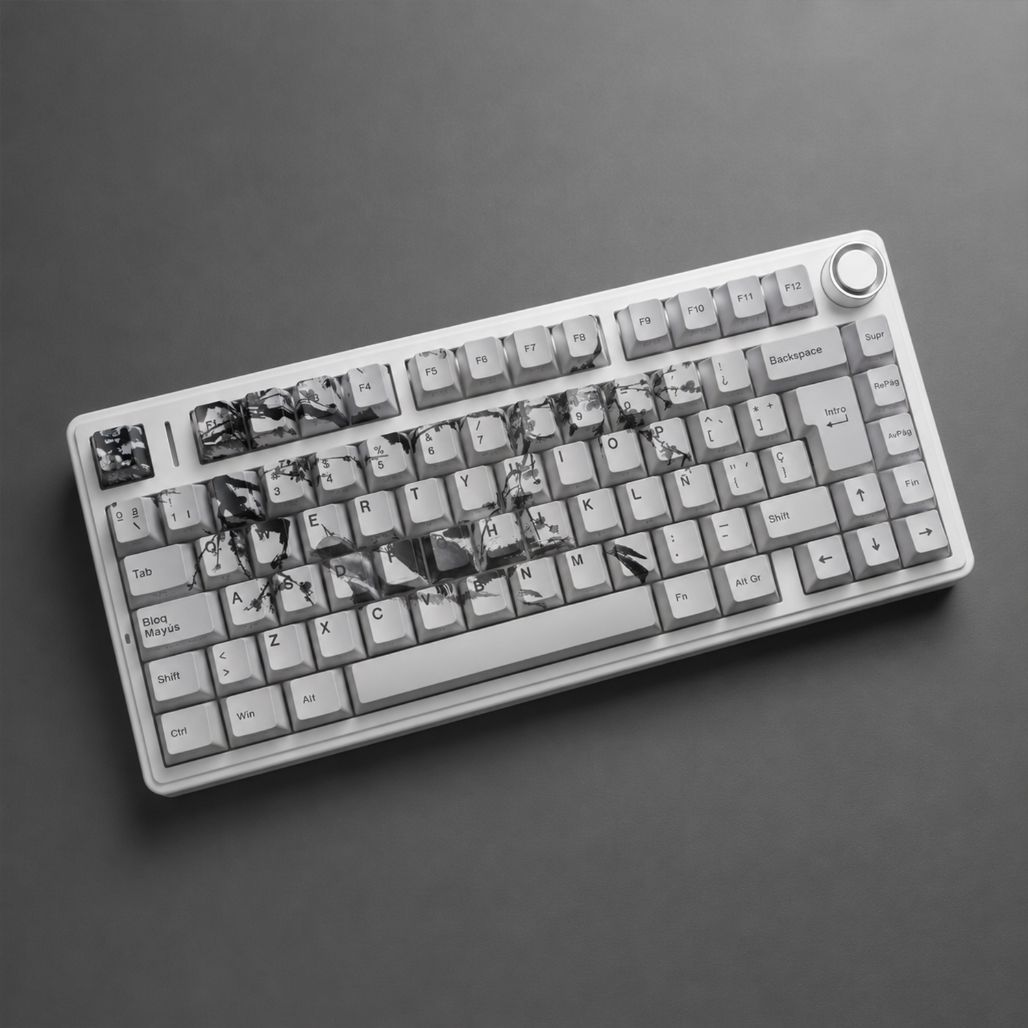 Teclado blanco con varias teclas rotas y agrietadas sobre un fondo gris (foto en blanco y negro)